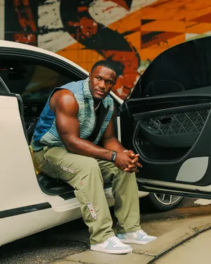 Stylish Man Seated Nextto Car Wallpaper