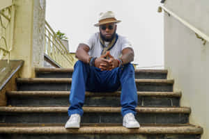 Stylish_ Man_ Seated_on_ Stairs Wallpaper