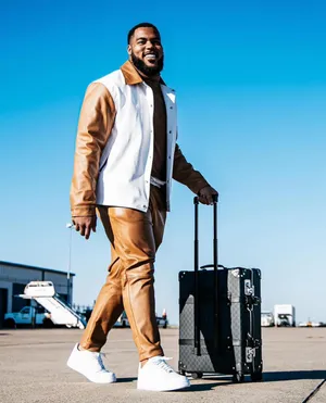 Stylish Manwith Suitcaseat Airport Wallpaper