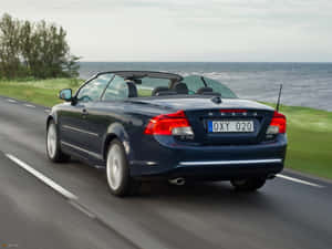 Stylish Volvo C70 Cruising On The Highway Wallpaper