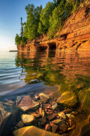 Sunlit_ Cliffside_and_ Calm_ Waters.jpg Wallpaper
