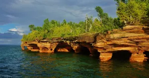 Sunlit_ Cliffside_ Over_ Water Wallpaper