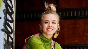 Sydney Sweeney Smiling Urban Backdrop Wallpaper