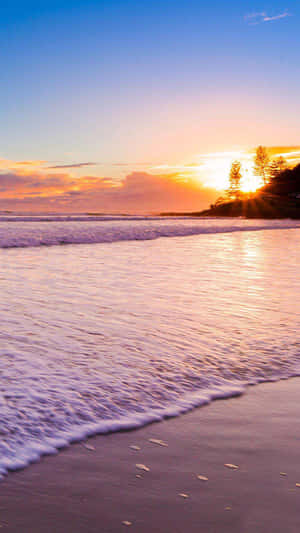 Take In The Beauty Of The Setting Sun On A Pristine Beach. Wallpaper
