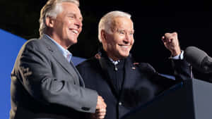 Terry Mcauliffe On A Podium With Joe Biden Wallpaper