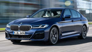 The 2020 Bmw 5 Series Sedan Is Driving Down The Street Wallpaper