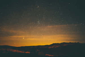 The Enchanting Night Sky Above The Hills Of A Village Wallpaper