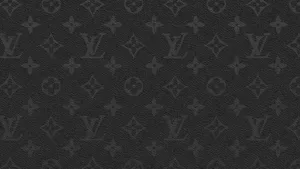 The Iconic Louis Vuitton Logo Atop A Brown Desktop Wallpaper