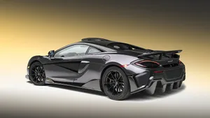 The Mclaren 600lt Speeding Along An Open Road Wallpaper