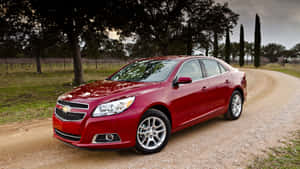 The Red Chevrolet Malibu Is Driving Down A Dirt Road Wallpaper