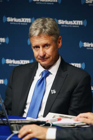 Thoughtful Gary Johnson Against Blue Backdrop Wallpaper