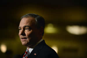 Thoughtful Tim Kaine In A Dimly Lit Room Wallpaper