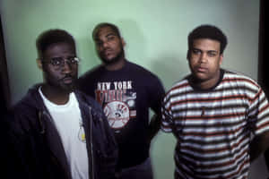 Three Men Standing Next To Each Other In A Green Room Wallpaper