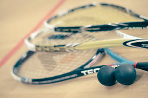 Three Racquetball Resting On The Floor Wallpaper