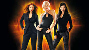 Three Women In Black Pants Standing In Front Of An Orange Background Wallpaper