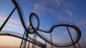 Thrilling Roller Coaster Illuminated At Night Wallpaper