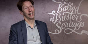 # Tim Blake Nelson Smiling During An Interview Wallpaper