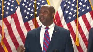 Tim Scott Standing Proudly In Front Of Three American Flags Wallpaper