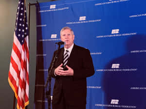 Tom Vilsack Saluting The American Flag Wallpaper