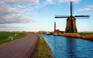 Traditional Dutch Windmill By Waterway Wallpaper
