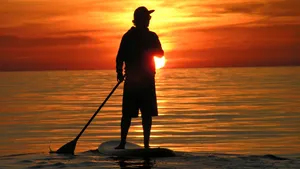 Tranquil Paddleboarding At Sunset Wallpaper