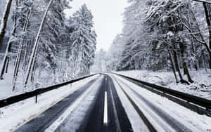 Tranquil Snowy Road Through A Winter Wonderland Wallpaper