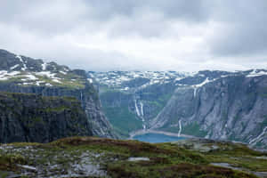 Trolltunga With Slight Snowy Peaks Wallpaper