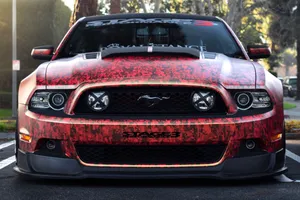 Two Bright Red Roses In A Glass Vase Standing Against A Brick Wall Wallpaper