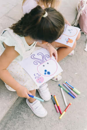 Two Girls Sitting On The Steps And Drawing With Markers Wallpaper