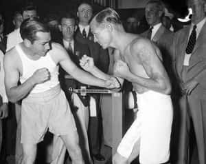Two Men In Boxing Shorts Fighting In Front Of A Crowd Wallpaper