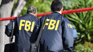 Two Men In Fbi Jackets Walking Down A Street Wallpaper