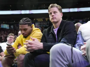 Two Men Sitting Court Sideat Sporting Event Wallpaper