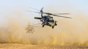 Two Military Helicopters Flying Over A Desert Wallpaper