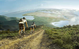 Two People Riding Bikes On A Dirt Road Wallpaper