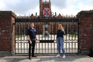 Two People Standing In Front Of A Gated Entrance Wallpaper