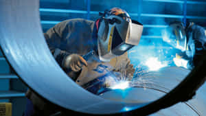 Two Welders Working On A Pipe Wallpaper