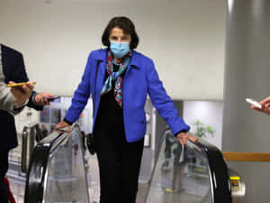 U.s. Senator Dianne Feinstein Wearing A Mask On An Escalator Wallpaper