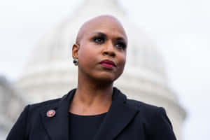 Us Representative Ayanna Pressley Posing With Serious Face In Front Of The Capitol Dome Wallpaper