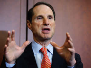 Us Senator Ron Wyden Actively Gesturing During A Speech Wallpaper