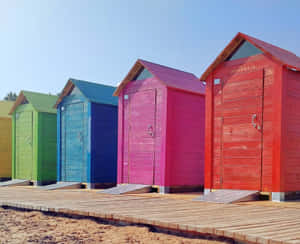 Vibrant Beach Huts Basking In The Sun Along The Shoreline Wallpaper