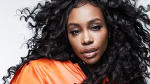 Vibrant Curly Haired Woman Orange Jacket Wallpaper