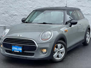 Vibrant Red Mini Cooper Hardtop 2 Door Displayed Against A Contrasting Serene Blurred Backdrop. Wallpaper