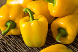 Vibrant Yellow Bell Pepper On A Wooden Surface Wallpaper