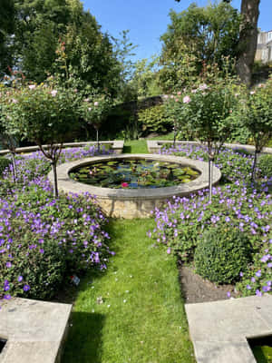 Victorian Garden Pond Surroundedby Flowers Wallpaper