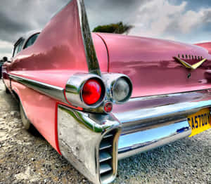 Vintage Pink Cadillac Parked Under Palm Trees Wallpaper