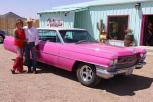 Vintage Pink Cadillac Under A Clear Blue Sky Wallpaper