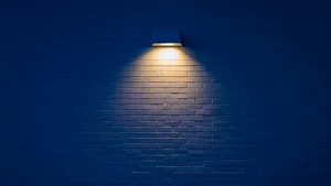 Wall Mounted Lamp Illuminating Bricks Wallpaper