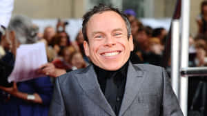 Warwick Davis Smiling In A Close-up Portrait Wallpaper