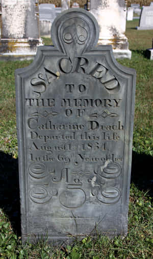 Weathered Gravestone In A Serene Cemetery Wallpaper