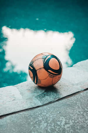 Weathered Soccer Ball Beside Pool Wallpaper